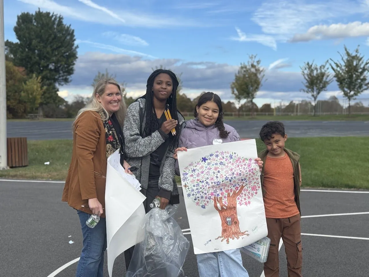 Friends holding a hand-painted tree from a children's class
